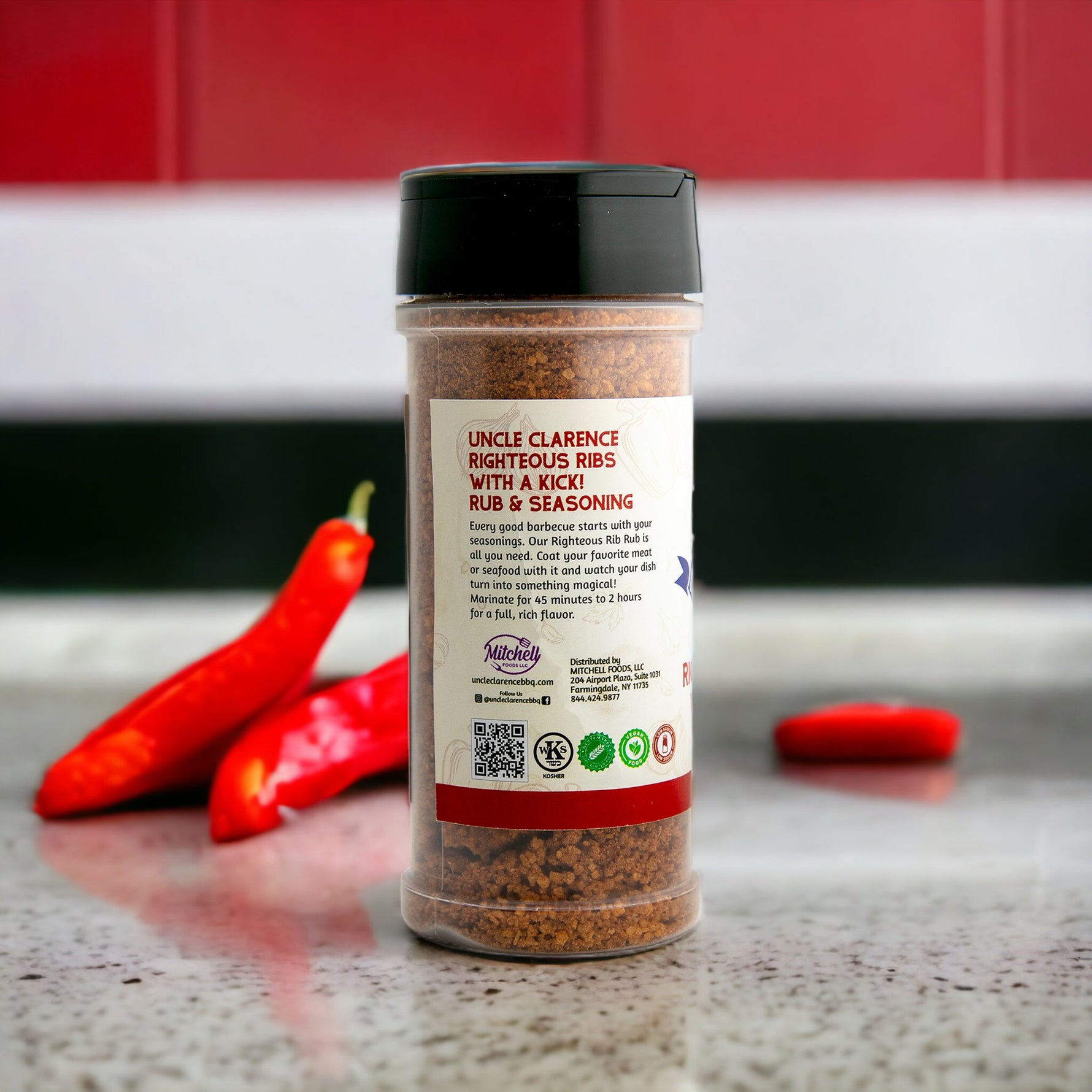 Uncle Clarence BBQ bold rib seasoning mix in a clear jar with red chili peppers in the background
