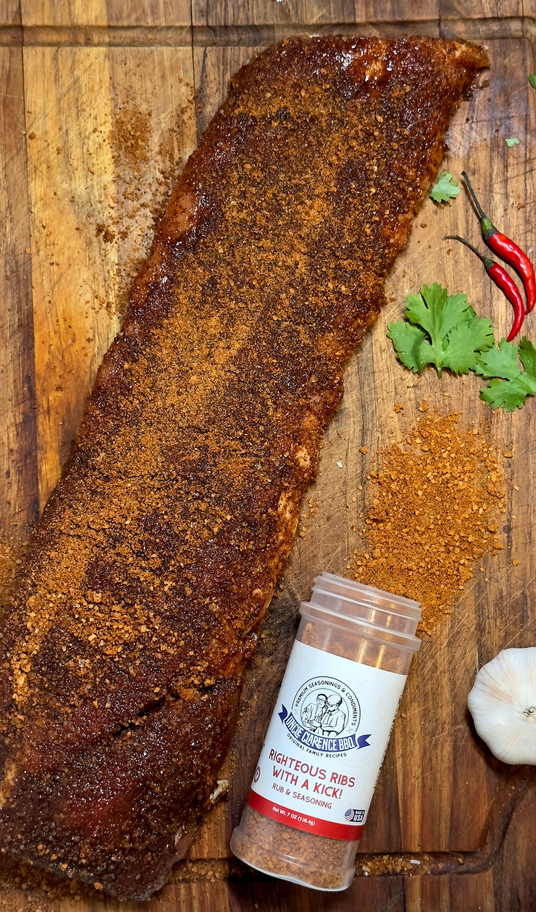 Uncle Clarence BBQ bold rib seasoning mix next to seasoned ribs on a wooden cutting board
