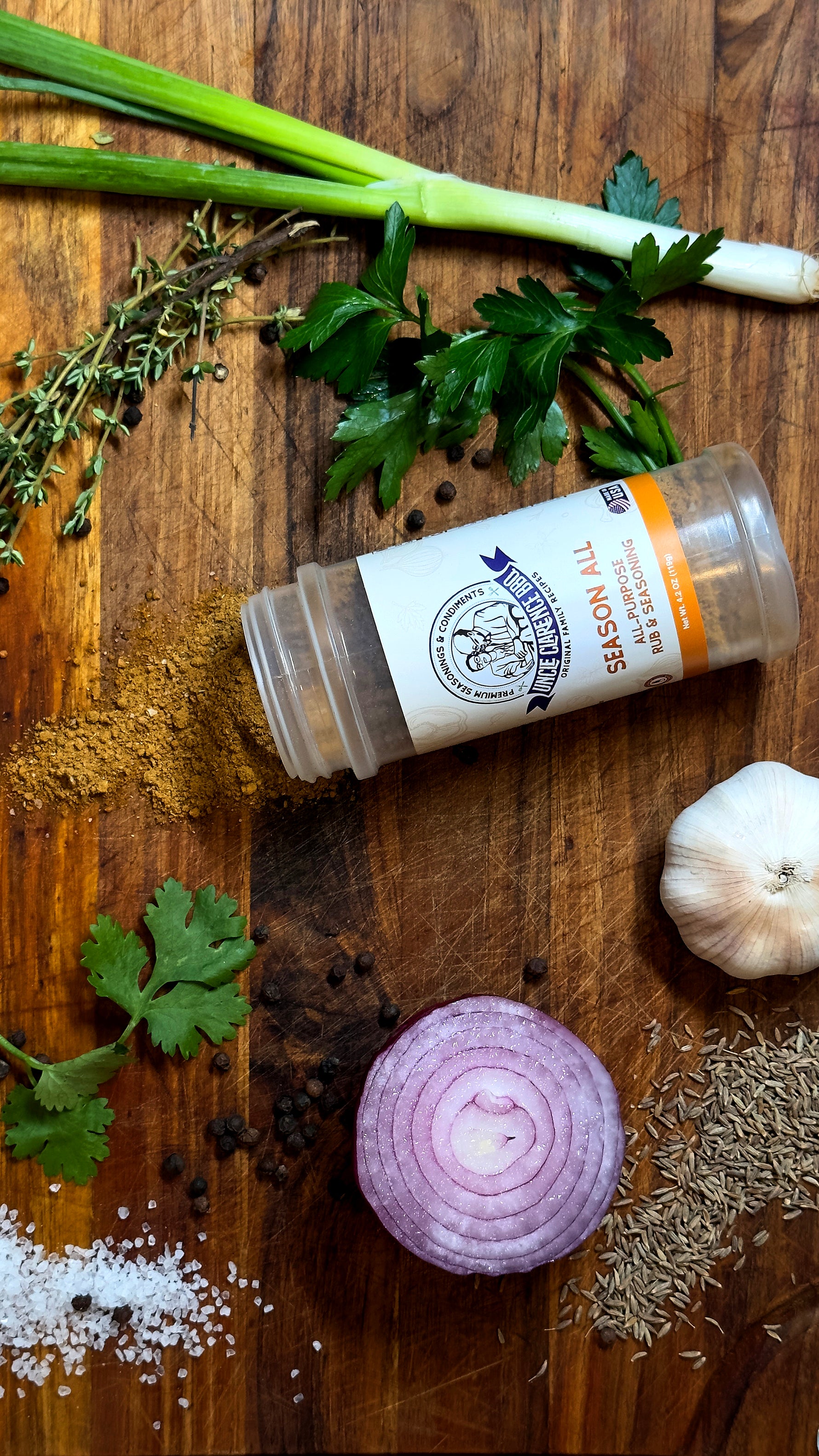 Uncle Clarence spice set displayed on a wooden cutting board with fresh herbs and spices