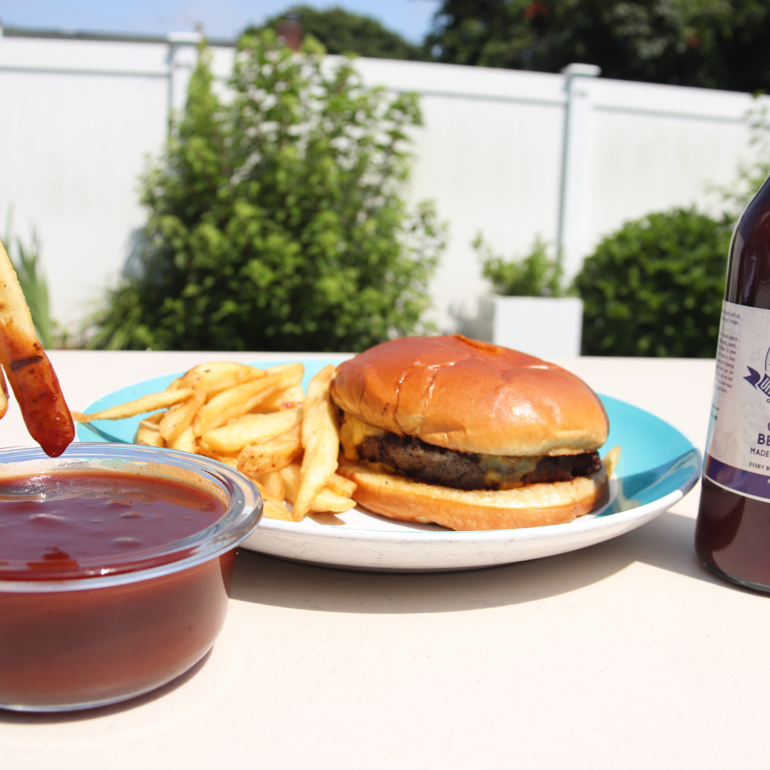 Unique barbecue sauce gift by Uncle Cl with a burger, fries, and dipping sauce outdoors